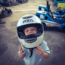 Menino pequeno em um capacete em uma pista de kart