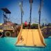 Boy coming down a slide into a swimming pool from a replica pirate ship