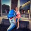 Little boy sat with a life-size artificial dolphin on a wooden bench