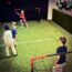 Boys playing football on a small indoor pitch