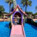 Petit garçon sur un toboggan en forme de maison dans une piscine